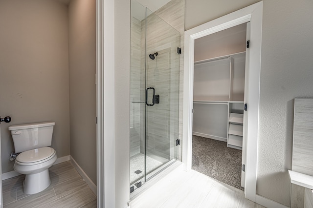 bathroom featuring toilet and a shower with shower door