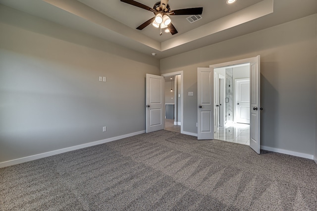 unfurnished bedroom featuring carpet floors, a tray ceiling, and ceiling fan