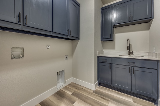 clothes washing area with cabinets, hookup for an electric dryer, gas dryer hookup, sink, and light hardwood / wood-style floors