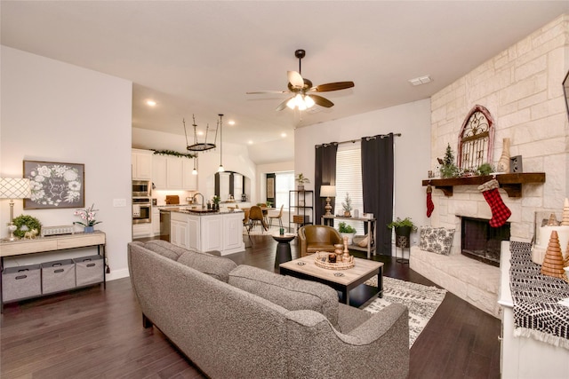 living room featuring dark wood-type flooring, ceiling fan, and a fireplace