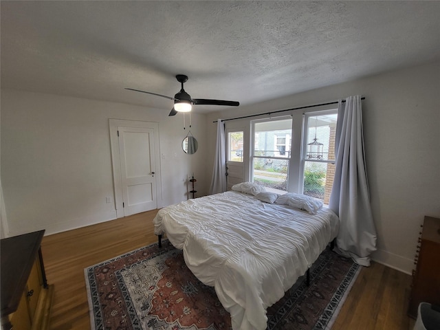 bedroom with a textured ceiling, dark hardwood / wood-style flooring, and ceiling fan