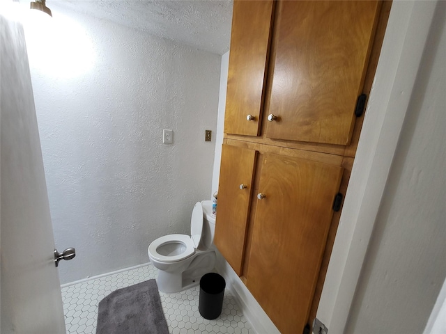 bathroom featuring tile patterned flooring, a textured ceiling, and toilet