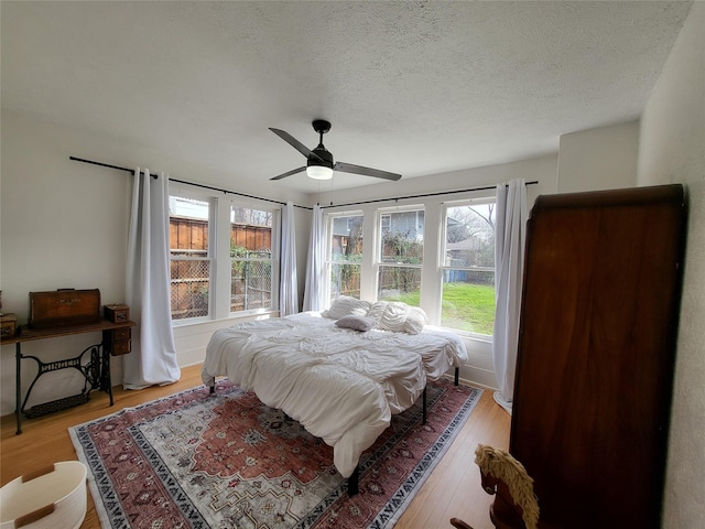 bedroom featuring a textured ceiling, light hardwood / wood-style flooring, and ceiling fan