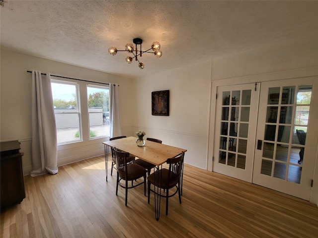 dining area featuring an inviting chandelier, a textured ceiling, and hardwood / wood-style flooring