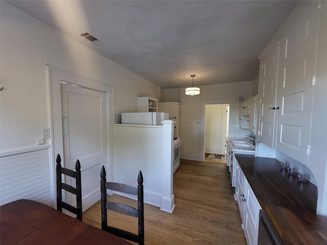 kitchen with white cabinetry, sink, pendant lighting, a textured ceiling, and hardwood / wood-style flooring