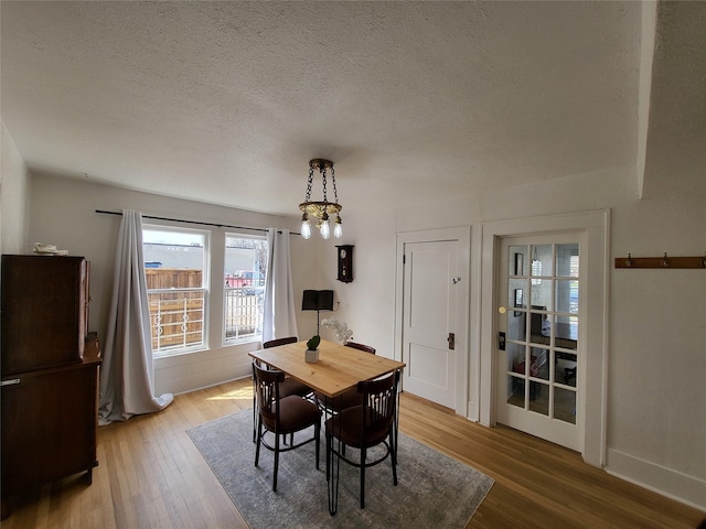 dining space featuring hardwood / wood-style flooring, a textured ceiling, and an inviting chandelier