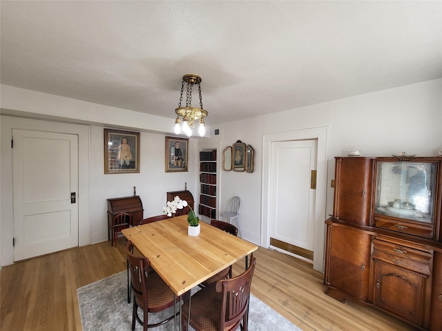 dining area with light hardwood / wood-style flooring and an inviting chandelier