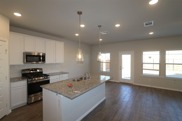 kitchen with stainless steel appliances, an island with sink, white cabinetry, and pendant lighting