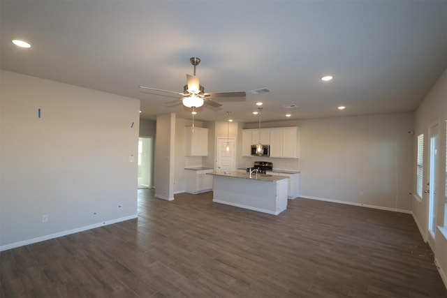 kitchen with visible vents, appliances with stainless steel finishes, open floor plan, a kitchen island with sink, and white cabinets