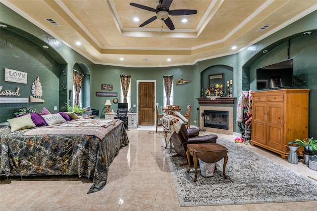 bedroom featuring a tray ceiling, crown molding, recessed lighting, visible vents, and a tile fireplace