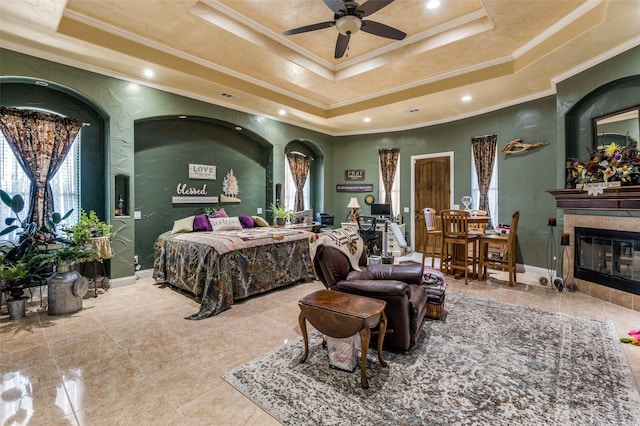 bedroom with a tray ceiling, a fireplace, visible vents, ornamental molding, and baseboards