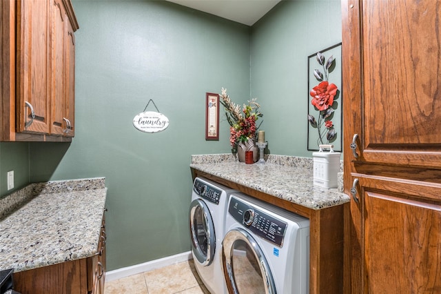 laundry room featuring cabinet space, light tile patterned floors, baseboards, and washing machine and clothes dryer