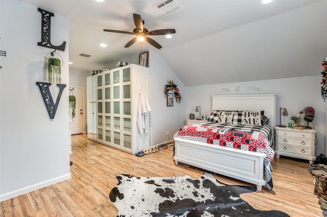 bedroom with light wood-type flooring, visible vents, vaulted ceiling, and baseboards