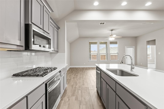 kitchen featuring gray cabinetry, stainless steel appliances, sink, light hardwood / wood-style floors, and lofted ceiling