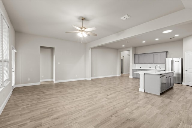 unfurnished living room featuring ceiling fan, sink, and light hardwood / wood-style floors