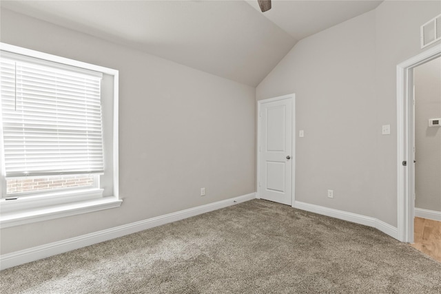 carpeted empty room with vaulted ceiling