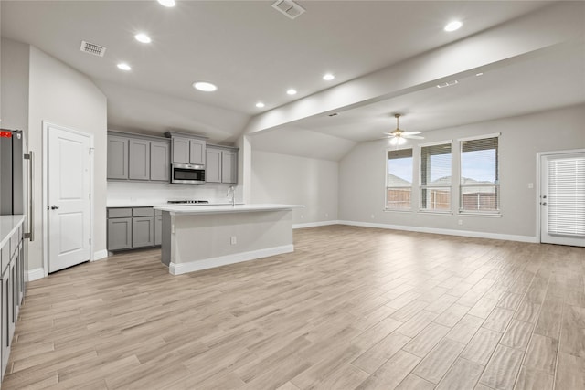 kitchen featuring gray cabinetry, lofted ceiling, light hardwood / wood-style flooring, ceiling fan, and appliances with stainless steel finishes