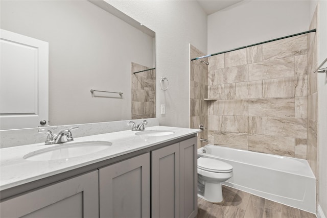 full bathroom with vanity, hardwood / wood-style floors, tiled shower / bath combo, and toilet