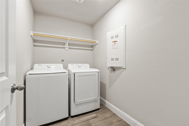 laundry area featuring washer and clothes dryer, electric panel, and light hardwood / wood-style flooring