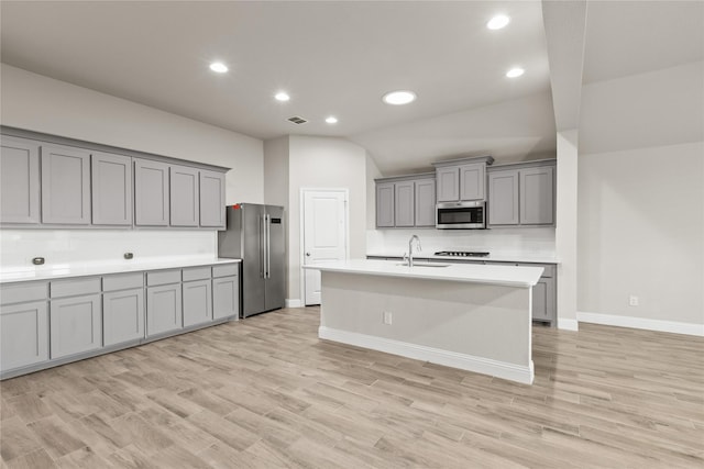 kitchen with light hardwood / wood-style flooring, stainless steel appliances, vaulted ceiling, and sink