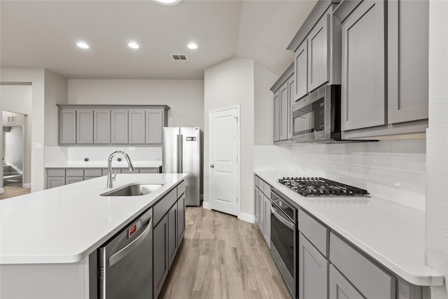 kitchen with gray cabinetry, light wood-type flooring, sink, and appliances with stainless steel finishes