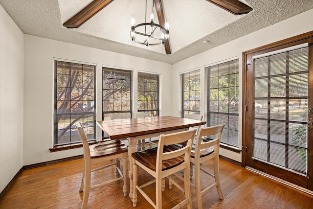 dining space with a chandelier, wood-type flooring, and a textured ceiling