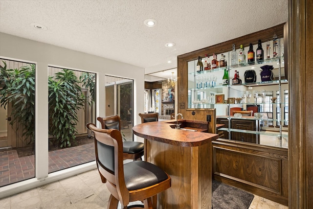 bar featuring sink and a textured ceiling