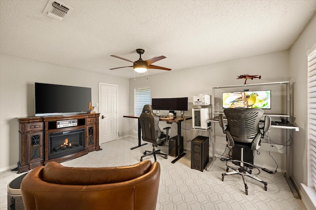 office space with ceiling fan, a textured ceiling, and light carpet