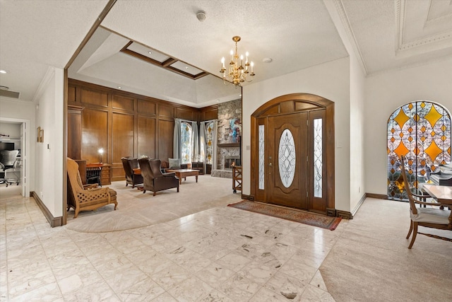 foyer with a chandelier, a textured ceiling, and ornamental molding