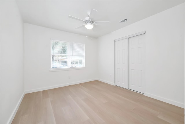 unfurnished bedroom featuring ceiling fan, a closet, and light wood-type flooring