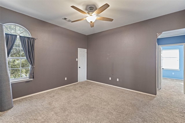 empty room featuring plenty of natural light, carpet floors, and ceiling fan