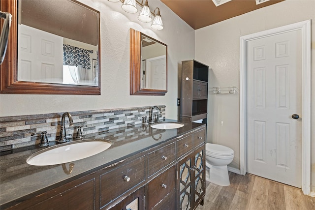 bathroom with tasteful backsplash, wood-type flooring, vanity, and toilet