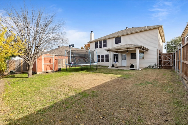 rear view of property featuring a yard, a patio, a shed, and a trampoline