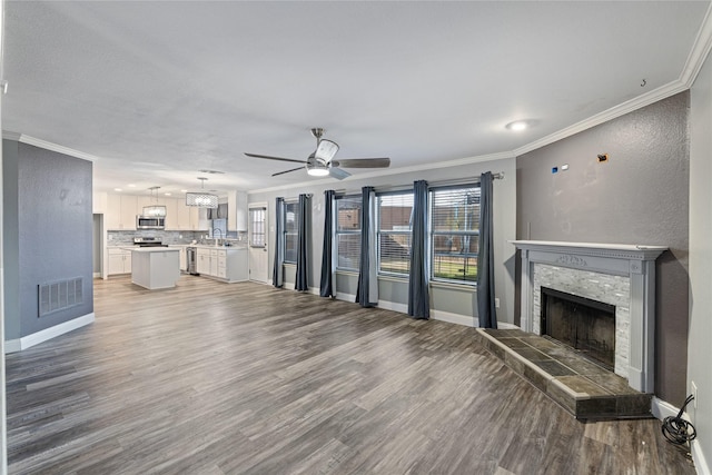 unfurnished living room featuring hardwood / wood-style flooring, a tile fireplace, ceiling fan, and crown molding