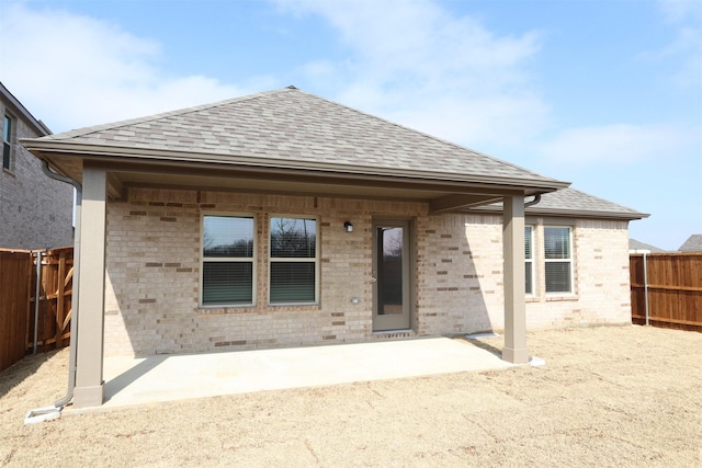 back of house featuring a patio area, a shingled roof, fence, and brick siding