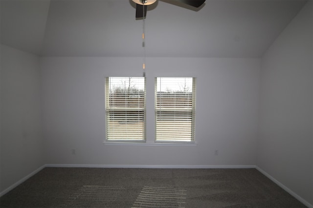 spare room featuring vaulted ceiling, dark carpet, a ceiling fan, and baseboards