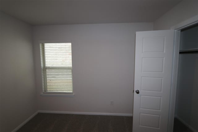 interior space featuring dark carpet and baseboards