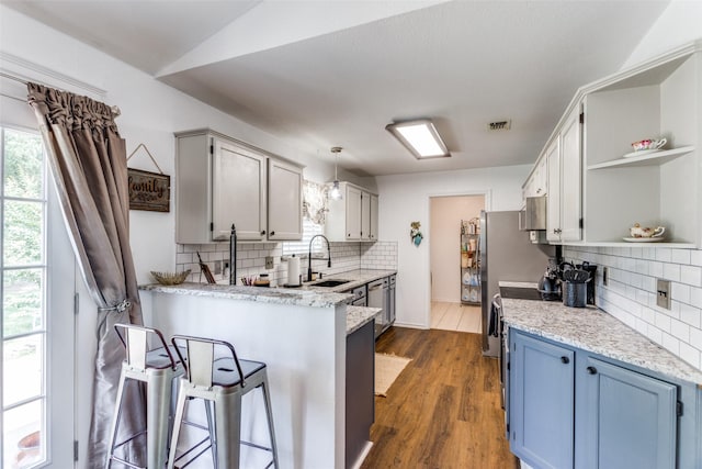 kitchen featuring sink, dark wood-type flooring, a kitchen breakfast bar, pendant lighting, and decorative backsplash