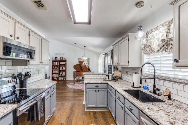 kitchen featuring decorative light fixtures, sink, lofted ceiling, and stainless steel appliances