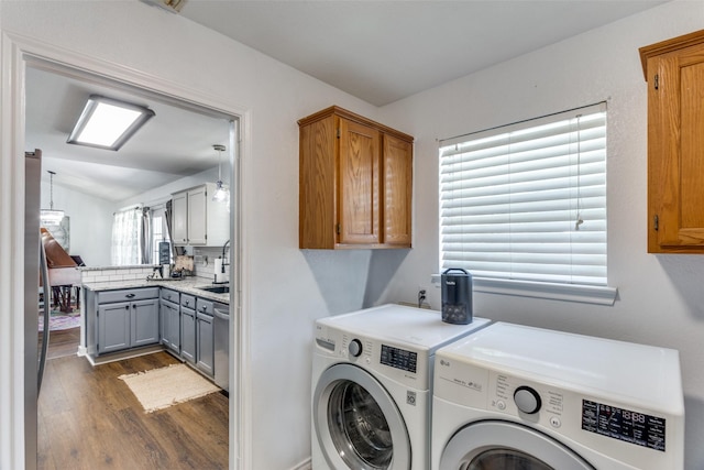 clothes washing area featuring plenty of natural light, cabinets, dark wood-type flooring, and washing machine and clothes dryer