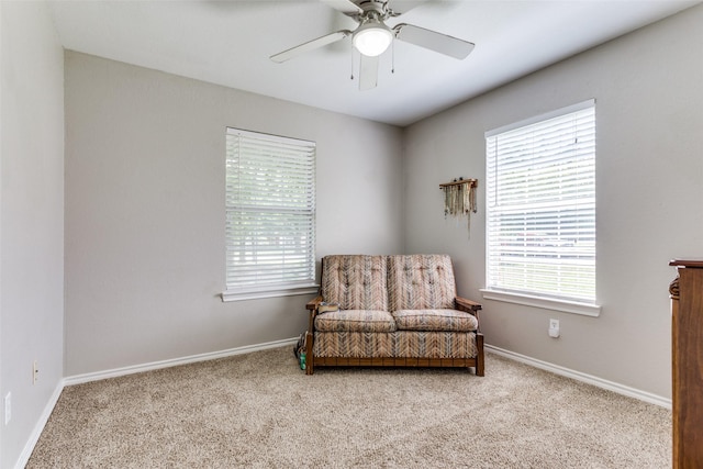 living area featuring a wealth of natural light, ceiling fan, and light carpet