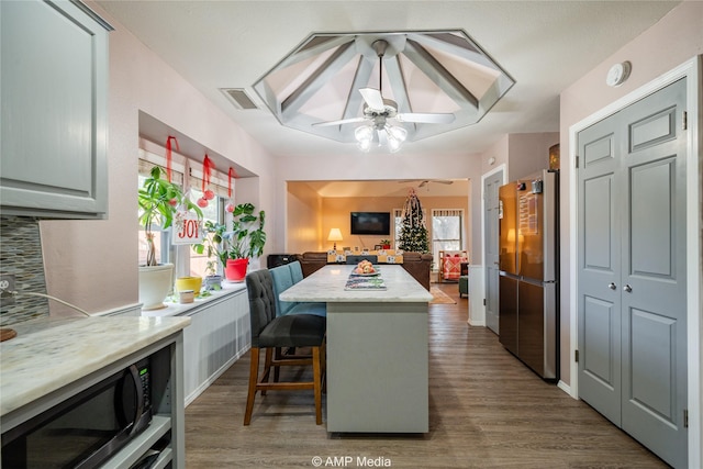 kitchen featuring stainless steel refrigerator, a kitchen bar, dark wood-type flooring, and a kitchen island