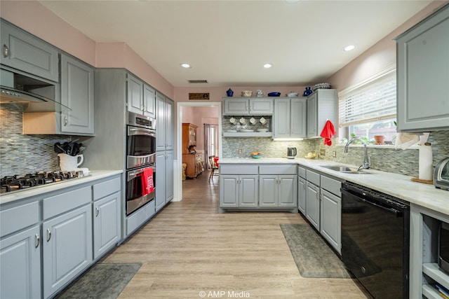 kitchen with sink, gray cabinetry, tasteful backsplash, light wood-type flooring, and appliances with stainless steel finishes