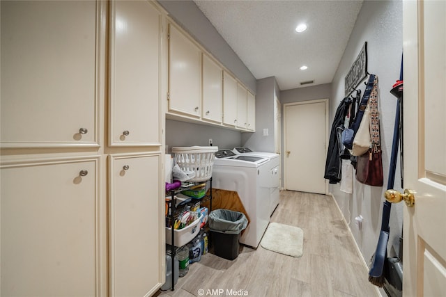 laundry area with cabinets, a textured ceiling, washer and dryer, and light wood-type flooring