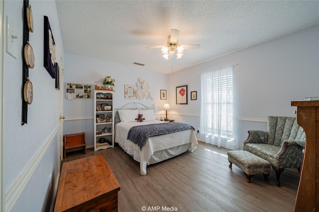 bedroom featuring ceiling fan, dark hardwood / wood-style floors, and a textured ceiling