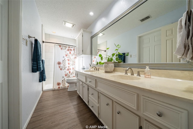 bathroom with walk in shower, toilet, wood-type flooring, a textured ceiling, and vanity