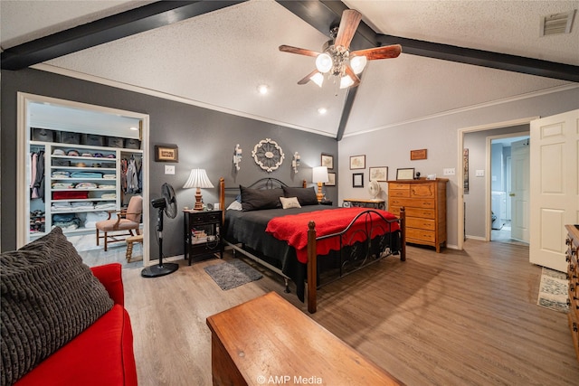 bedroom featuring ceiling fan, wood-type flooring, lofted ceiling with beams, and a textured ceiling