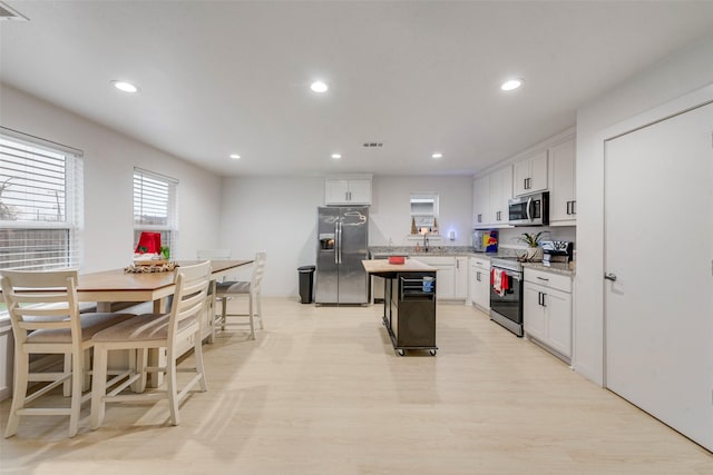 kitchen with a breakfast bar area, a center island, white cabinets, and appliances with stainless steel finishes