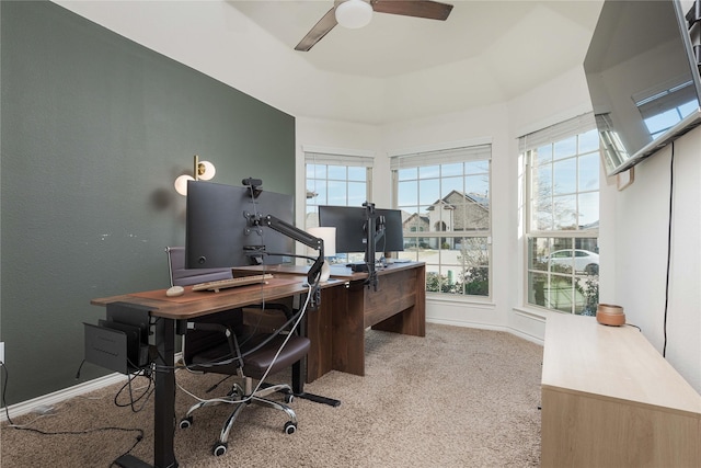 office space with ceiling fan, light carpet, and a tray ceiling