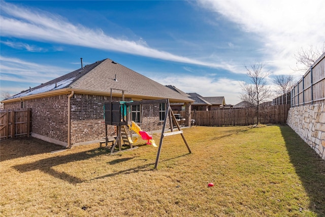 back of property featuring a yard and a playground